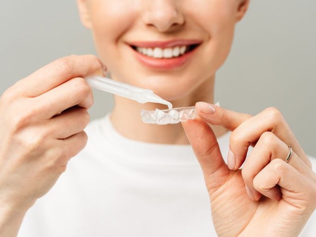 Paciente sorrindo após clareamento dental supervisionado em consultório odontológico