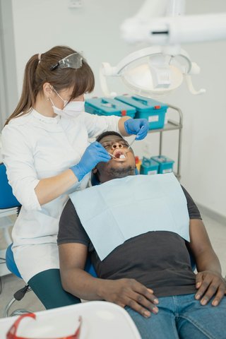 Cirurgiã-dentista examinando paciente no consultório antes de procedimento de extração