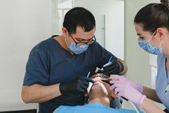 Dois profissionais de odontologia realizando limpeza dental em paciente no consultório