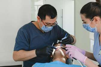 Dois profissionais de odontologia realizando limpeza dental em paciente no consultório