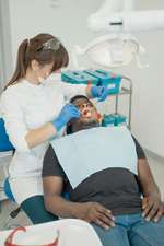 Cirurgiã-dentista examinando paciente no consultório antes de procedimento de extração